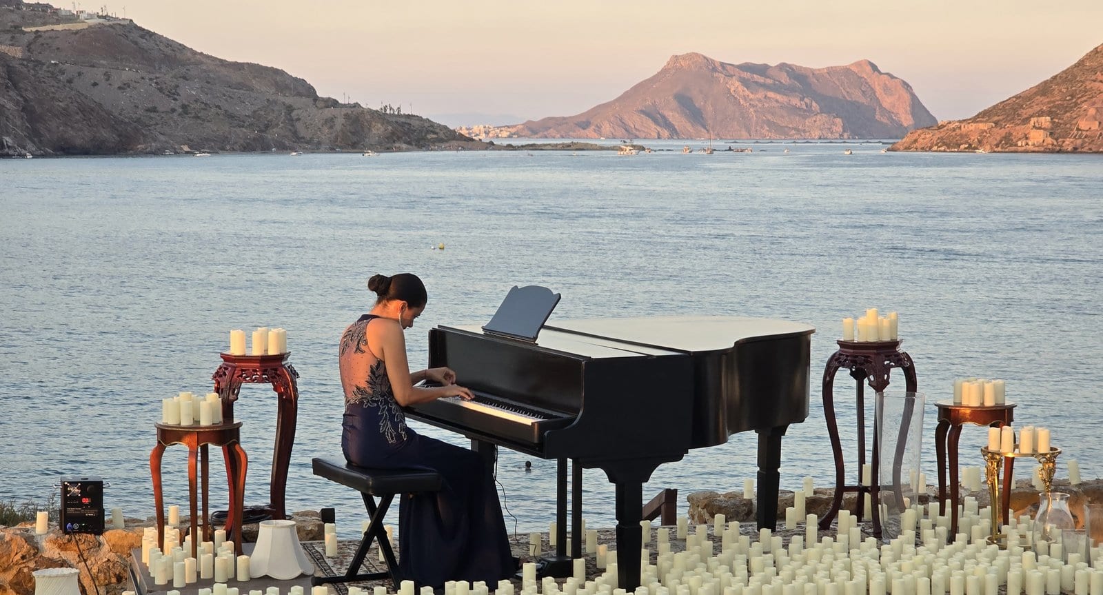 Joanna González al piano junto al mar al atardecer